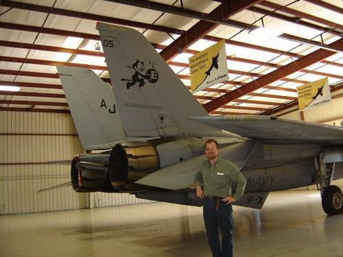 Niel Malan posing at the tailplane of an F-15 figher aircraft.