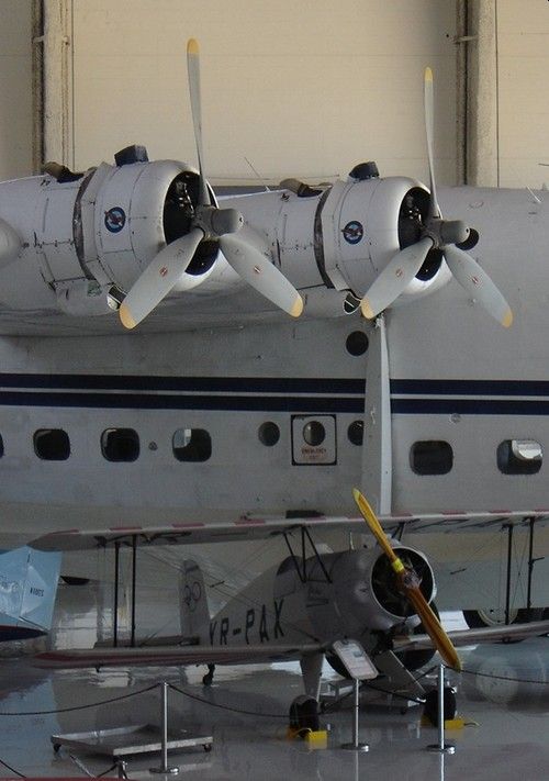 The starbord engines of a Short Sunderland flying boat, with a biplane parked under it.